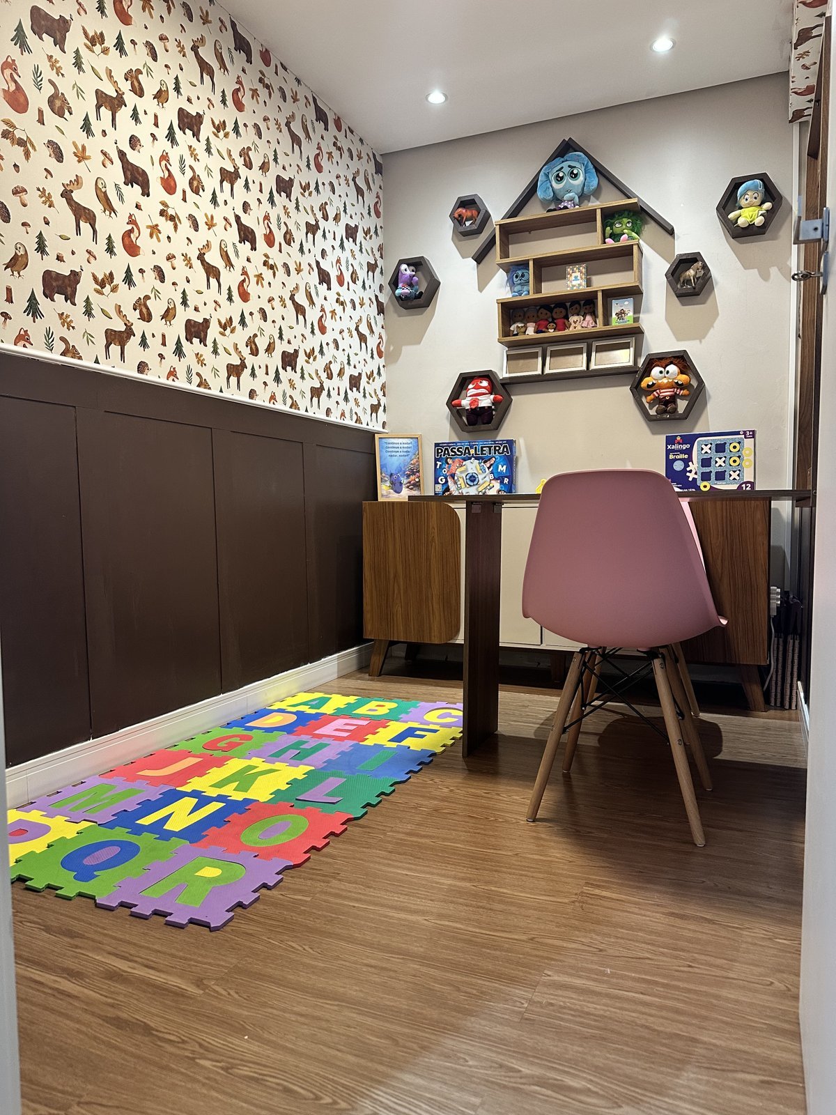 Sala com mesa, cadeiras, estantes e recursos lúdicos para atendimento